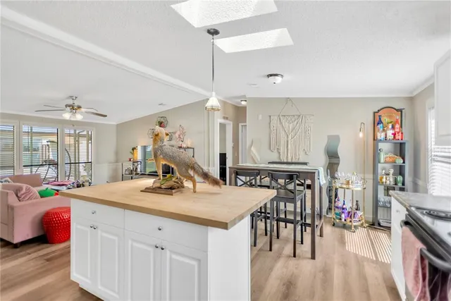 a kitchen that has a lot of white furniture a window and wooden floor