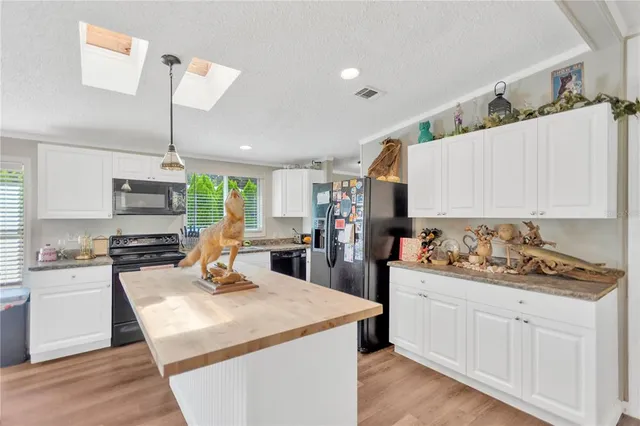 a kitchen with stainless steel appliances kitchen island granite countertop a stove and white cabinets