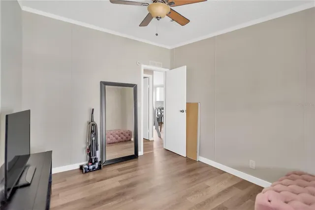 a view of a room with wooden floor a ceiling fan and staircase