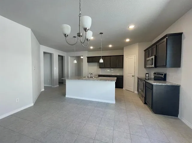 a large kitchen with kitchen island granite countertop a sink counter space cabinets and stainless steel appliances