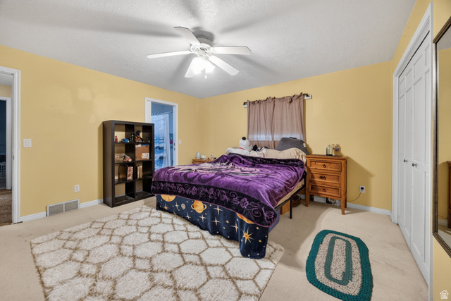 1218 East 100 South Logan, UT 84321 - Photo 13 of 23 Spacious bedroom featuring light-colored walls, ceiling fan with light fixture, light-toned carpet, and a bi-fold closet with mirrored panel