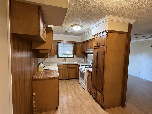 a kitchen with granite countertop a refrigerator a sink dishwasher stove and oven