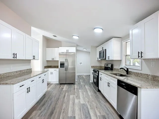 a large kitchen with stainless steel appliances granite countertop a lot of counter space and wooden floors