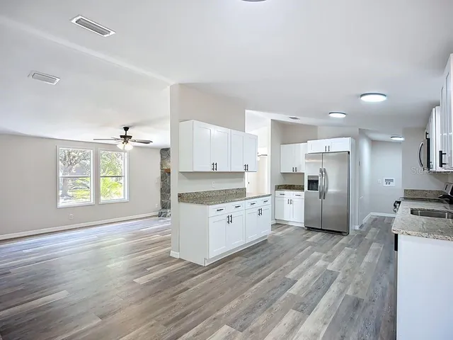 a kitchen with granite countertop a stove a sink and a refrigerator
