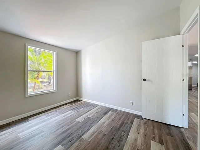 a view of an empty room with wooden floor and a window