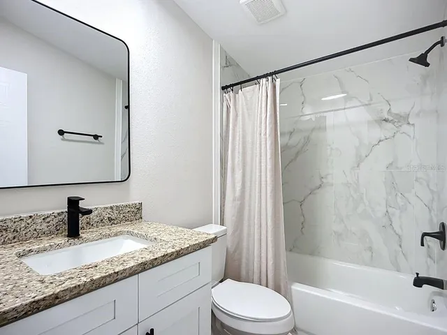 a bathroom with a granite countertop sink toilet and shower