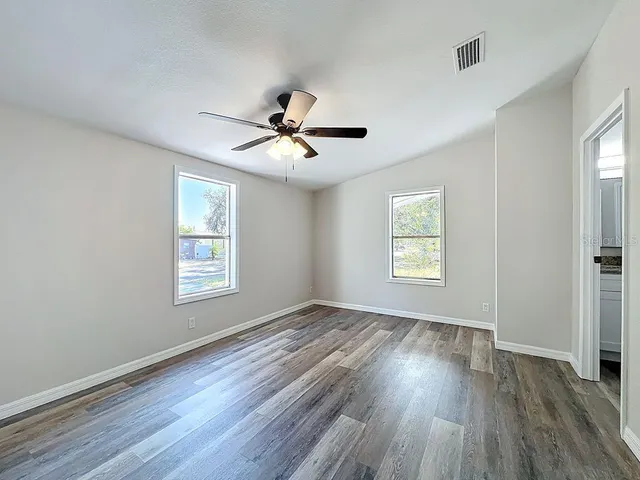 a view of an empty room with a window and wooden floor