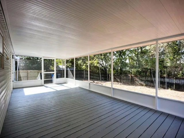 a view of an empty room with wooden floor and glass door