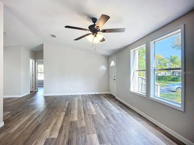 a view of empty room with wooden floor and fan
