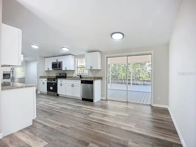 a large kitchen with kitchen island a stove a sink dishwasher and white cabinets with wooden floor