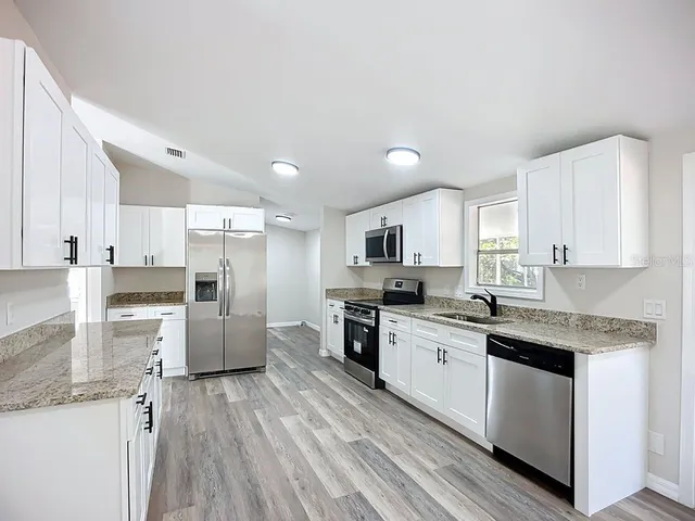 a kitchen with stainless steel appliances a refrigerator sink and white cabinets