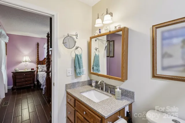 a en suite bathroom with a granite countertop sink and a mirror