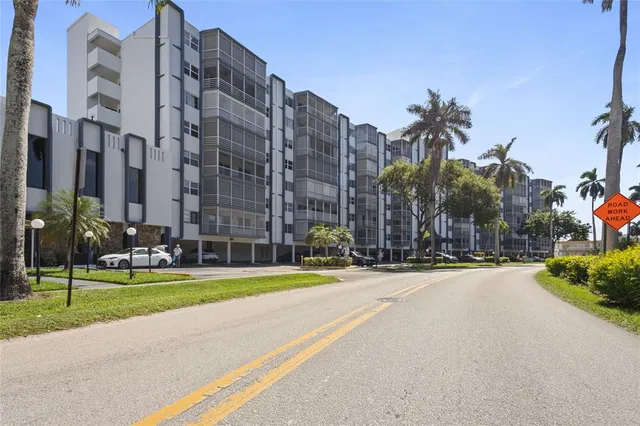 a view of a tall building next to a big yard and large trees
