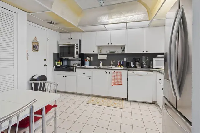 a kitchen with stainless steel appliances a sink a stove a refrigerator cabinets and a window