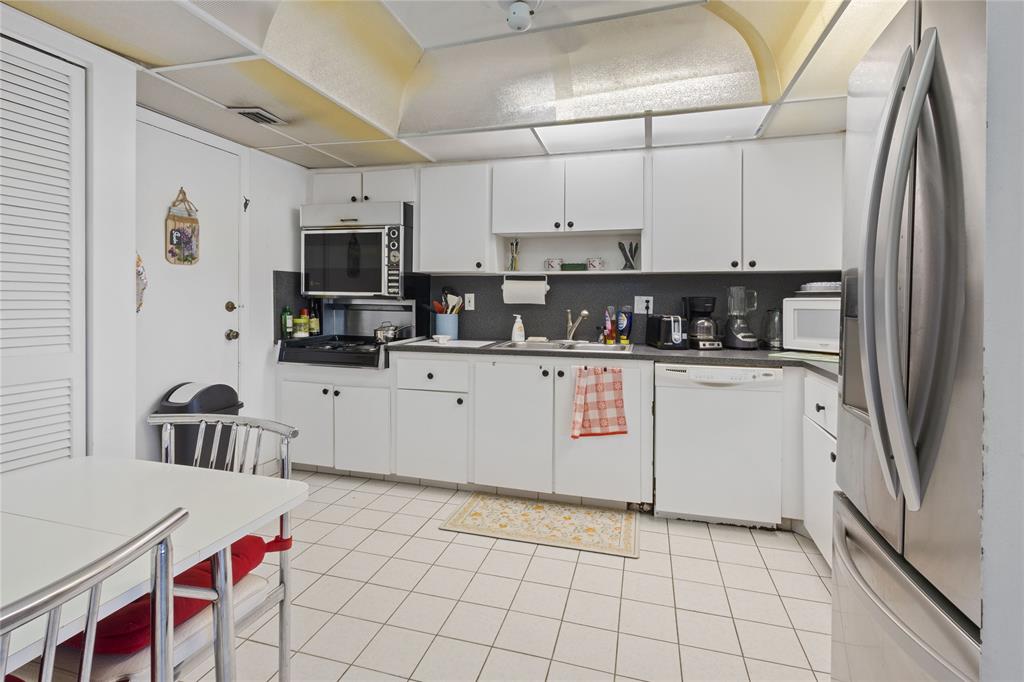 200 Diplomat Parkway, Unit 520 Hallandale Beach, FL 33009 - Photo 4 of 17 a kitchen with stainless steel appliances a sink a stove a refrigerator cabinets and a window