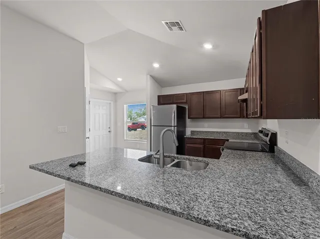 a view of a kitchen with refrigerator and wooden floor