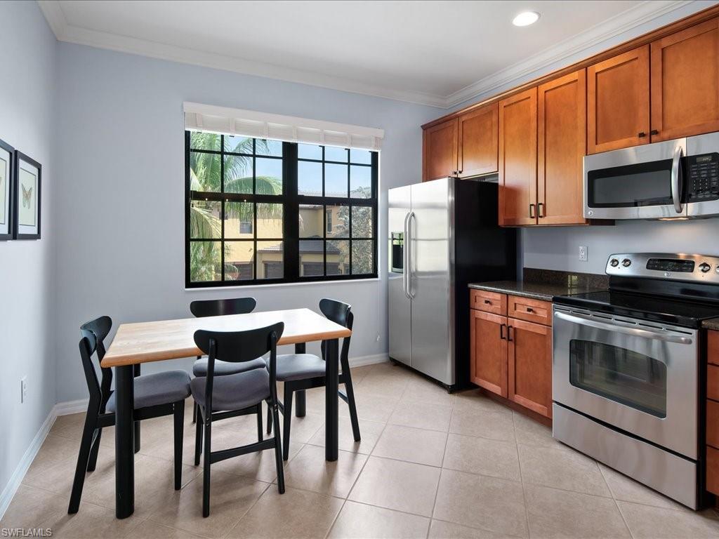 8985 Cambria Circle, Unit 215 Naples, FL 34113 - Photo 13 of 36 a kitchen with stainless steel appliances granite countertop a stove a refrigerator a microwave oven with a dining table and chairs