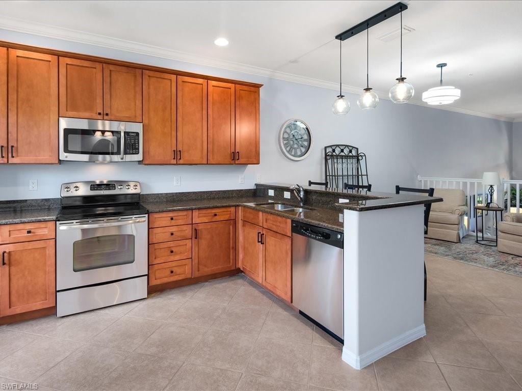 8985 Cambria Circle, Unit 215 Naples, FL 34113 - Photo 14 of 36 a kitchen with stainless steel appliances granite countertop a sink a stove and a microwave