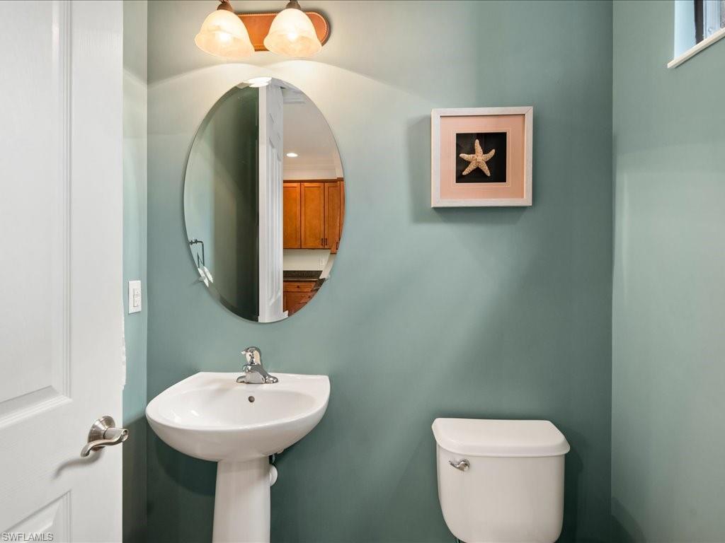 8985 Cambria Circle, Unit 215 Naples, FL 34113 - Photo 16 of 36 a bathroom with a toilet sink and mirror