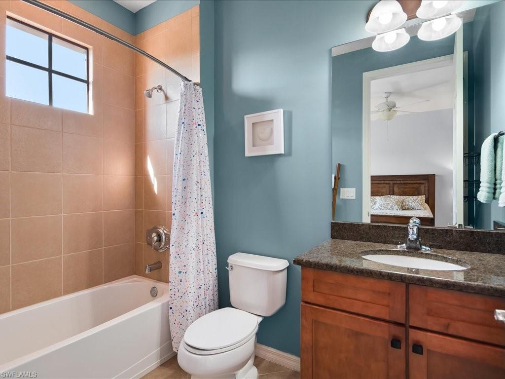 8985 Cambria Circle, Unit 215 Naples, FL 34113 - Photo 22 of 36 a bathroom with a sink a toilet a mirror a vanity a bathtub and shower
