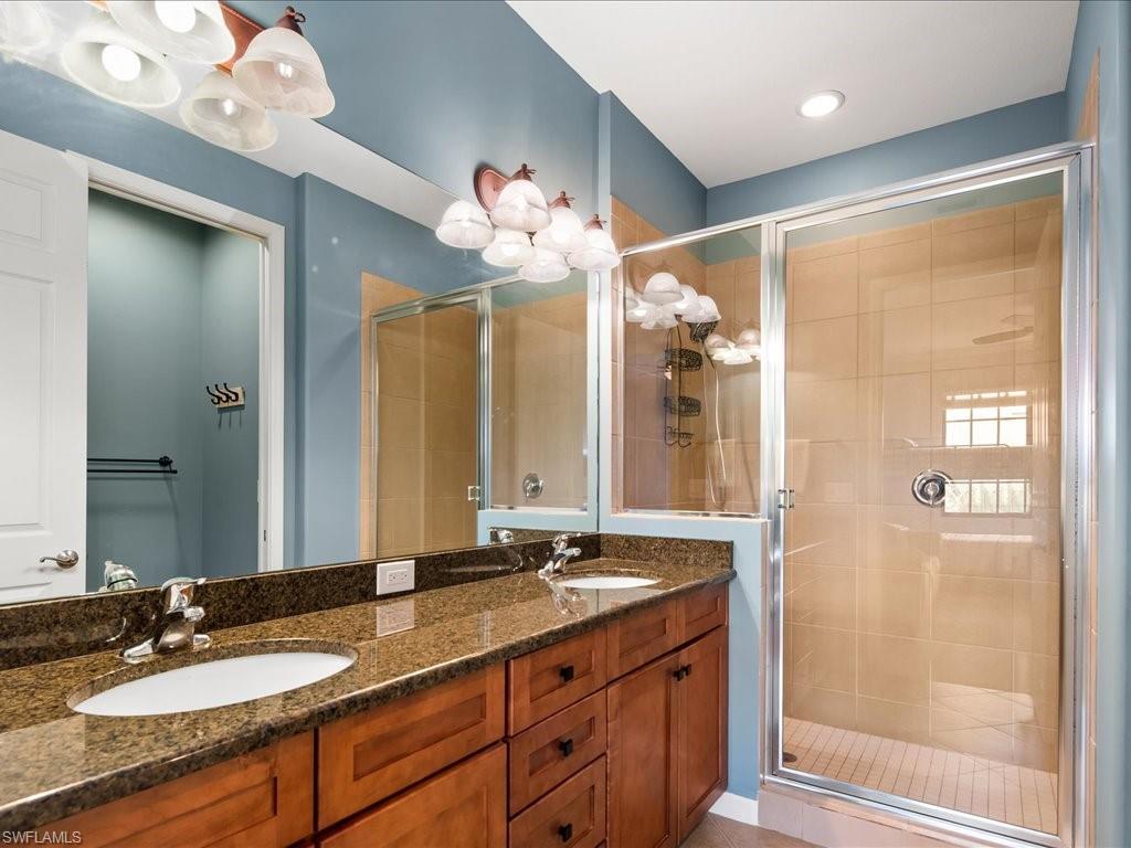 8985 Cambria Circle, Unit 215 Naples, FL 34113 - Photo 25 of 36 a bathroom with a granite countertop sink mirror and a shower