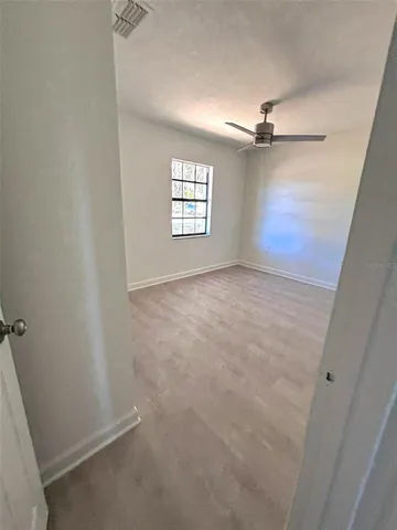 an empty room with windows and fan