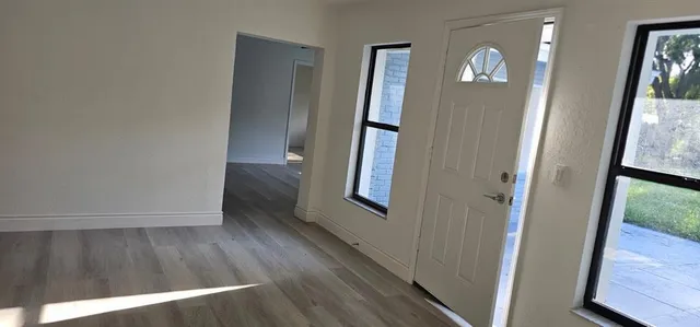 an entryway with wooden floor and a mirror