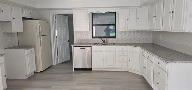 a kitchen with white cabinets and refrigerator