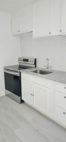 a kitchen with granite countertop white cabinets and white stainless steel appliances
