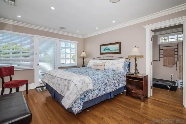a bedroom with a bed a dresser and wooden floor