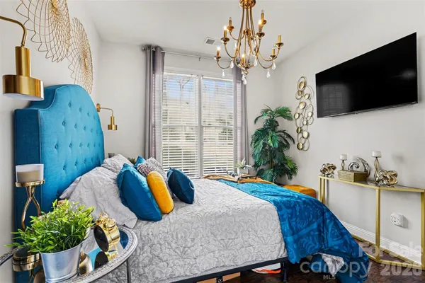 a bedroom with a bed a flat screen tv and a chandelier