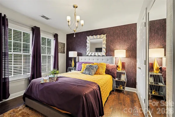 a bedroom with a bed lamps and a large mirror on the dresser