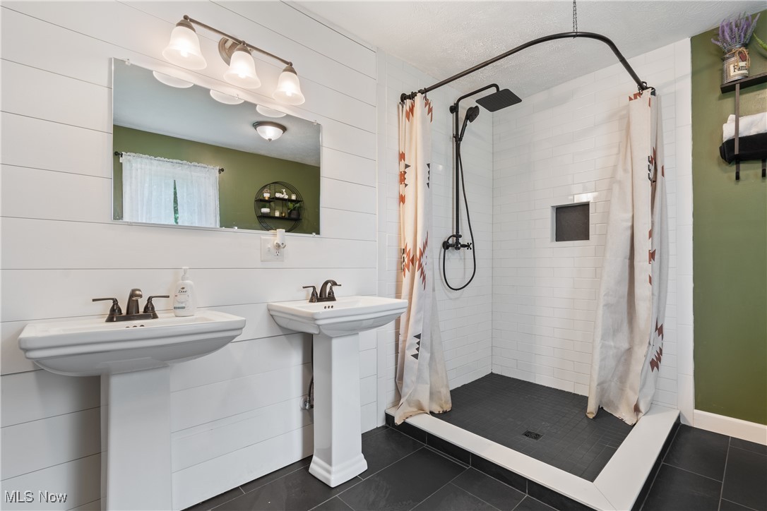 3609 Mahoning Road Northeast Canton, OH 44705 - Photo 16 of 31 Full bath with dark tile patterned flooring, a shower stall, a textured ceiling, and wood walls