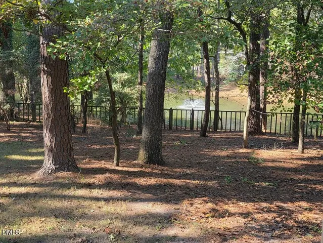 a view of a yard with large trees and a barn