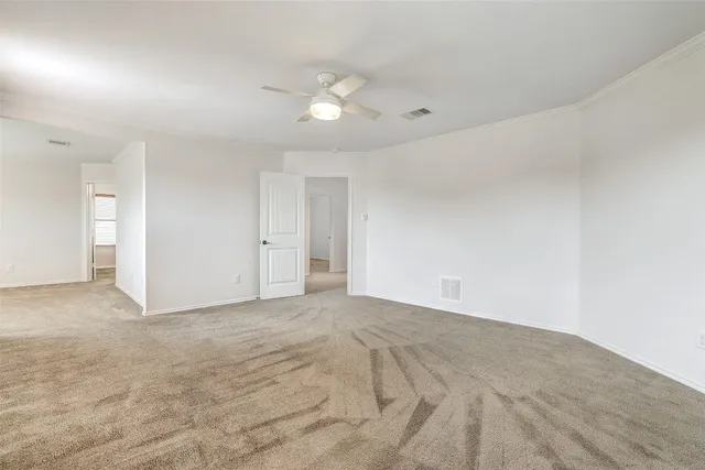 a view of an empty room with chandelier fan