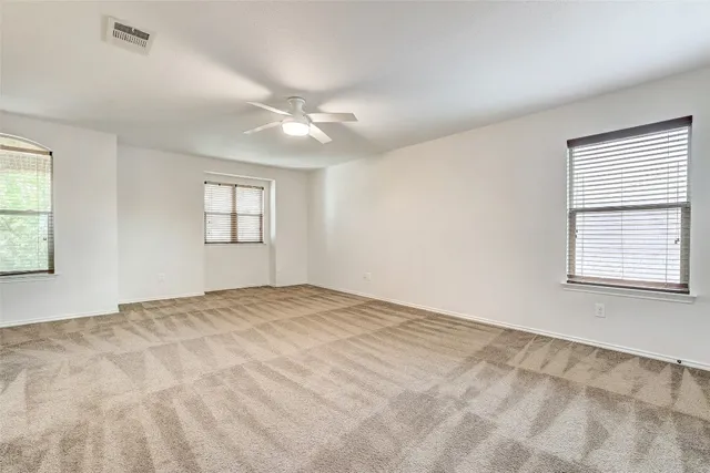 a view of an empty room with window and chandelier fan
