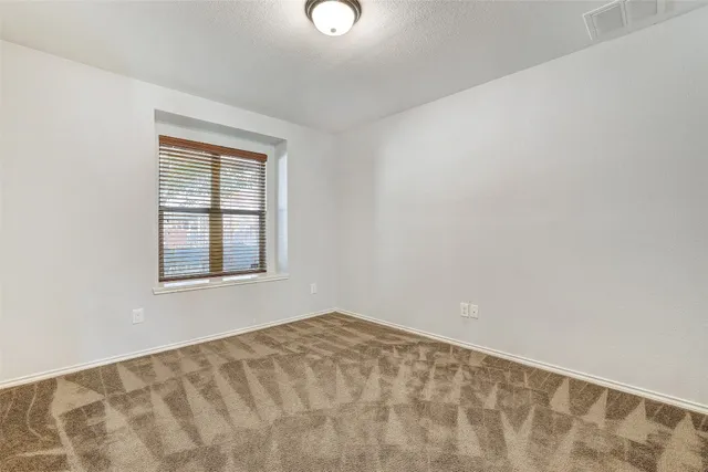 an empty room with chandelier fan and windows