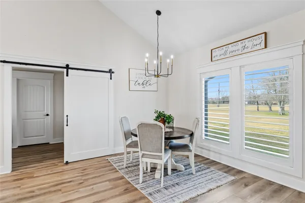a dining room with wooden floor a chandelier a wooden table and chairs