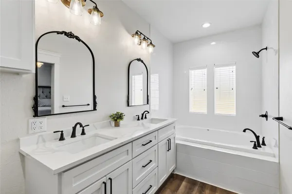 a bathroom with a double vanity sink and mirror with bathtub