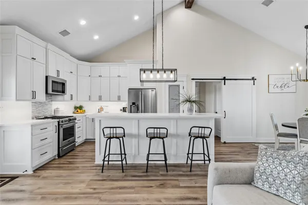 a kitchen with stainless steel appliances granite countertop a kitchen island hardwood floor sink and stove