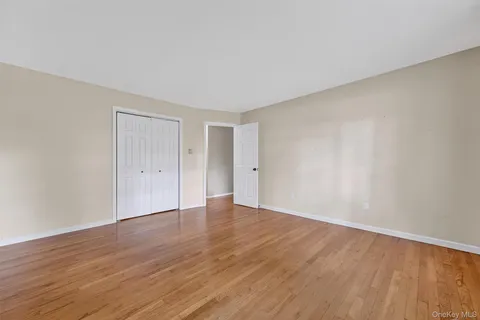 a view of an empty room with wooden floor and closet