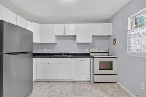 a kitchen with granite countertop white cabinets white stainless steel appliances and sink