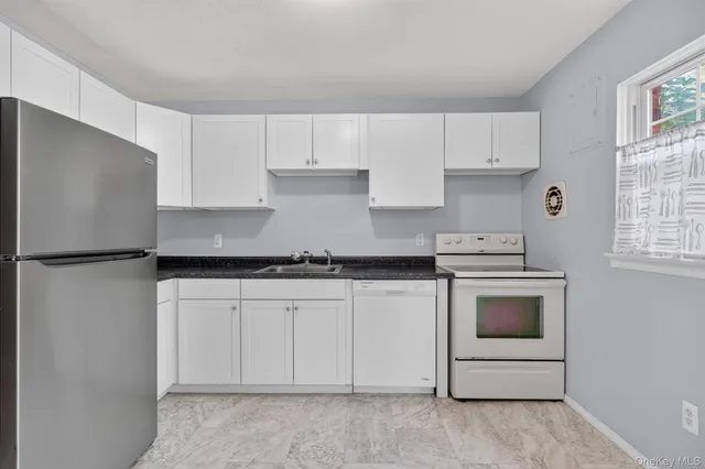 a kitchen with granite countertop white cabinets white stainless steel appliances and sink