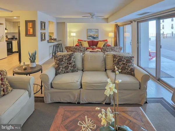 a living room with couches and a flat screen tv with kitchen view