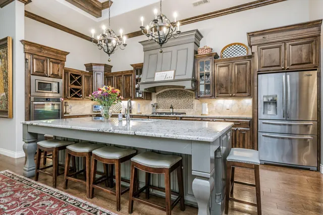 a kitchen with granite countertop a table chairs cabinets stainless steel appliances and wooden floor