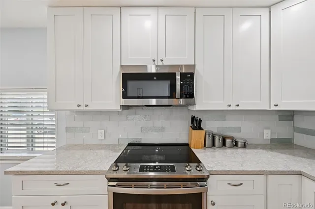 a kitchen with granite countertop white cabinets and white stainless steel appliances