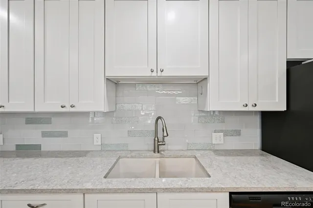 a kitchen with granite countertop white cabinets and a sink
