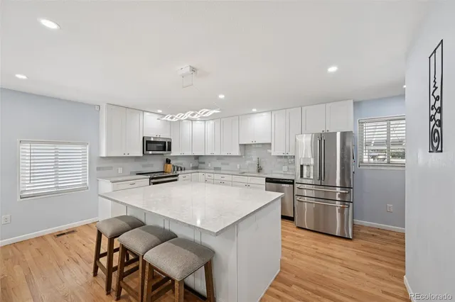 a kitchen with stainless steel appliances a refrigerator a stove a sink dishwasher and a refrigerator with wooden floor