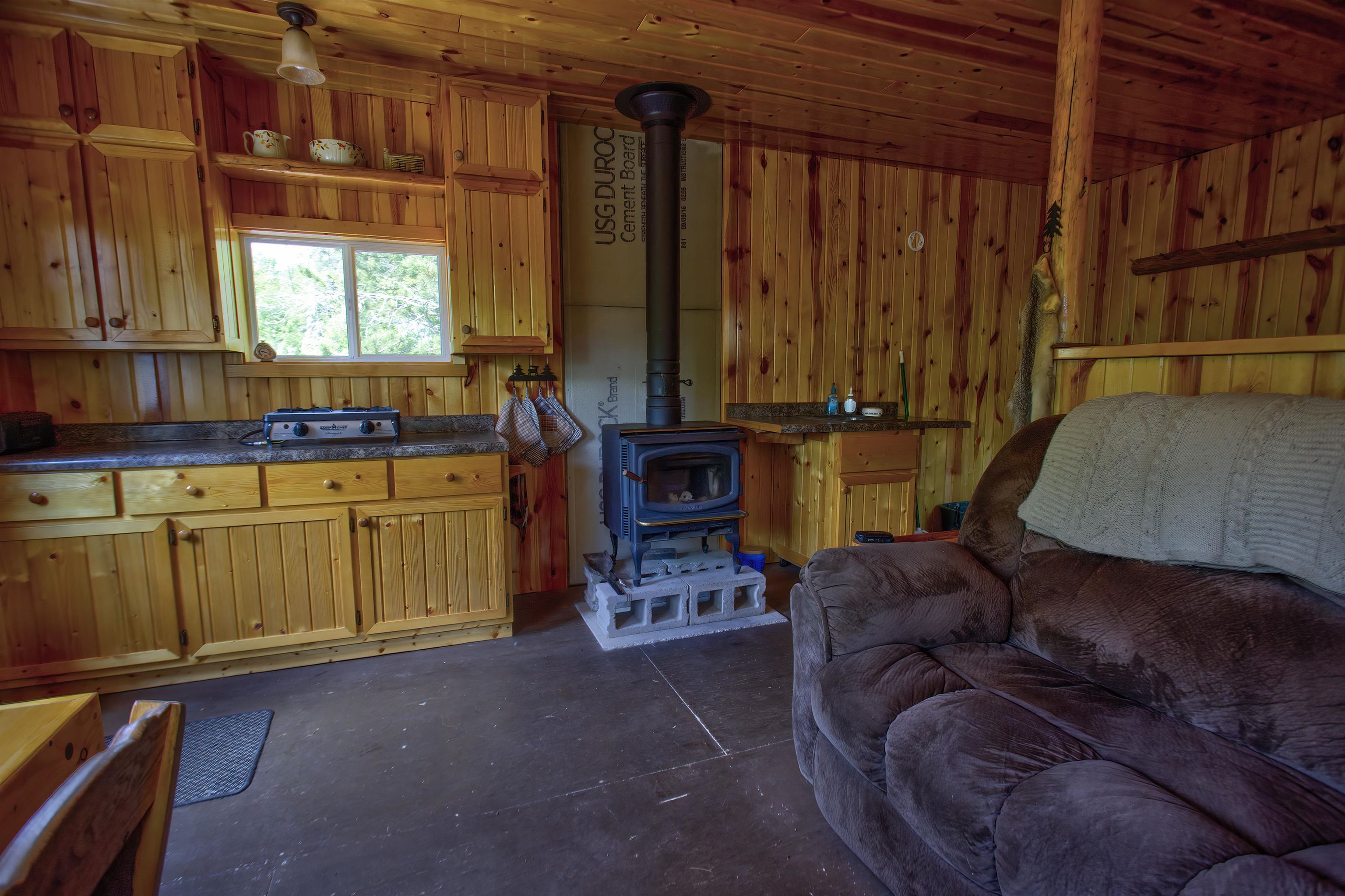 4194 Nels Lake Road Ely, MN 55731 - Photo 27 of 27 Kitchen featuring a wood stove, concrete floors, dark countertops, wooden walls, and open floor plan