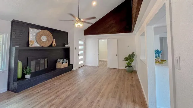 a view of an empty room with wooden floor and a fireplace